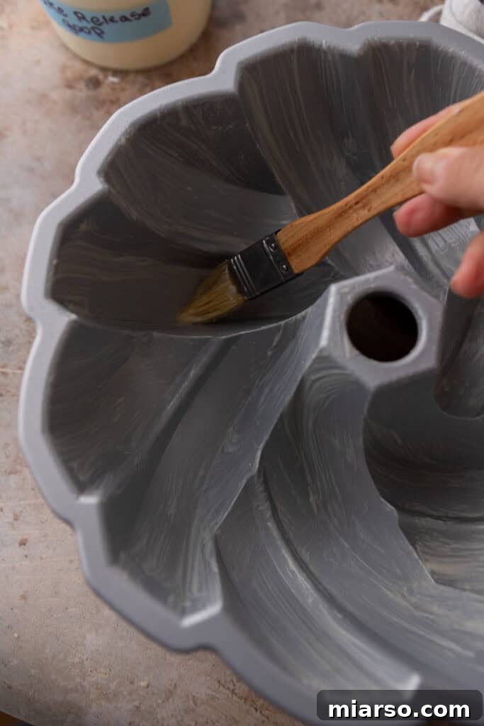 Pastry brush applying cake release to a baking pan.