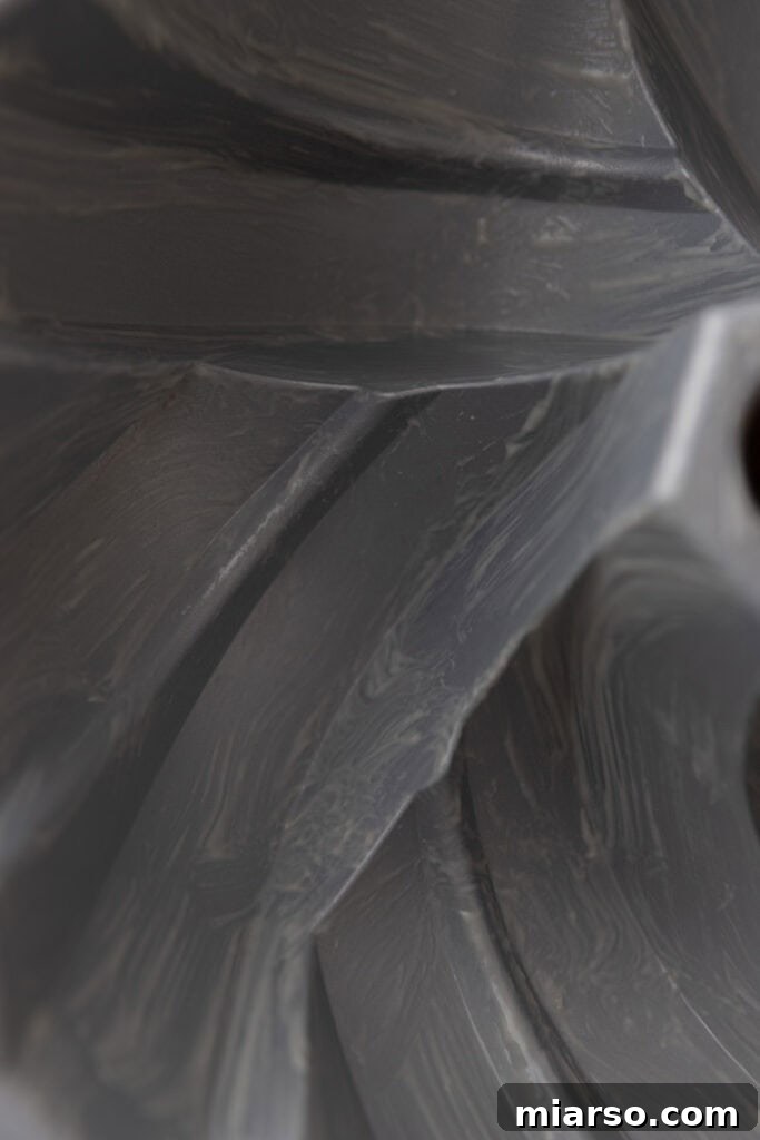 Close-up of a pastry brush applying cake release to the intricate details of a pan.