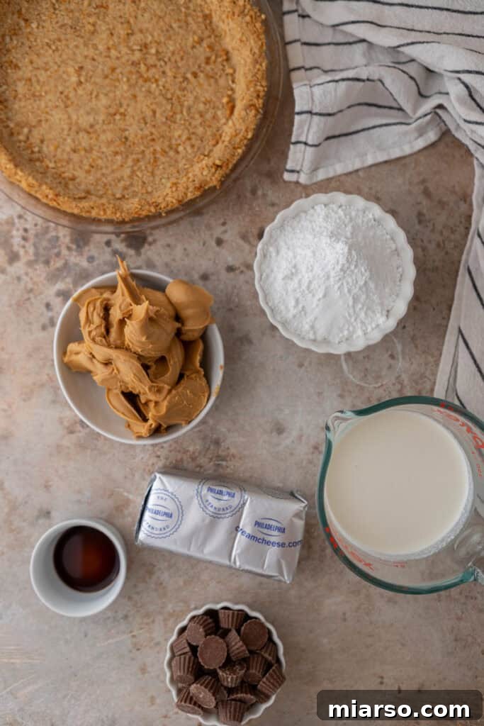 All the fresh ingredients laid out on a wooden surface, ready to make a no-bake peanut butter pie, including graham crackers, peanut butter, cream cheese, and heavy cream.