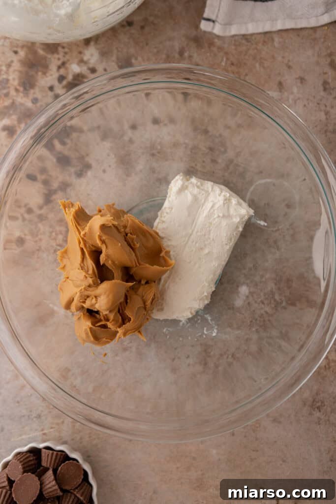 Unmixed cream cheese and peanut butter in a mixing bowl, ready to be beaten.