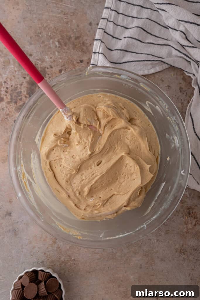 Whipped heavy cream with stiff peaks in a bowl, showcasing the ideal consistency before folding into the filling.