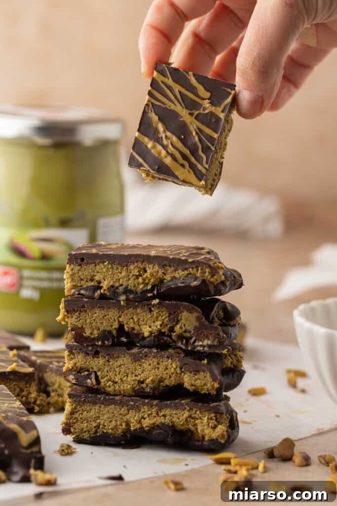 A hand holding a piece of Dubai Chocolate Date Bark, ready to be eaten.