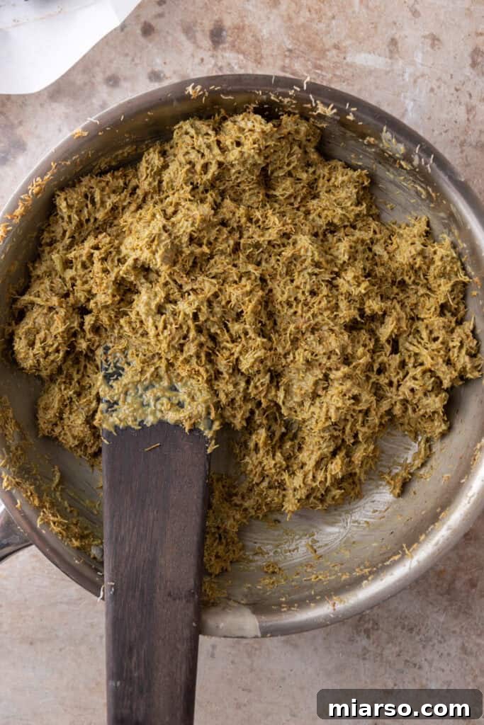 The mixed pistachio-tahini-kataifi layer spread evenly over the date base on a baking sheet.