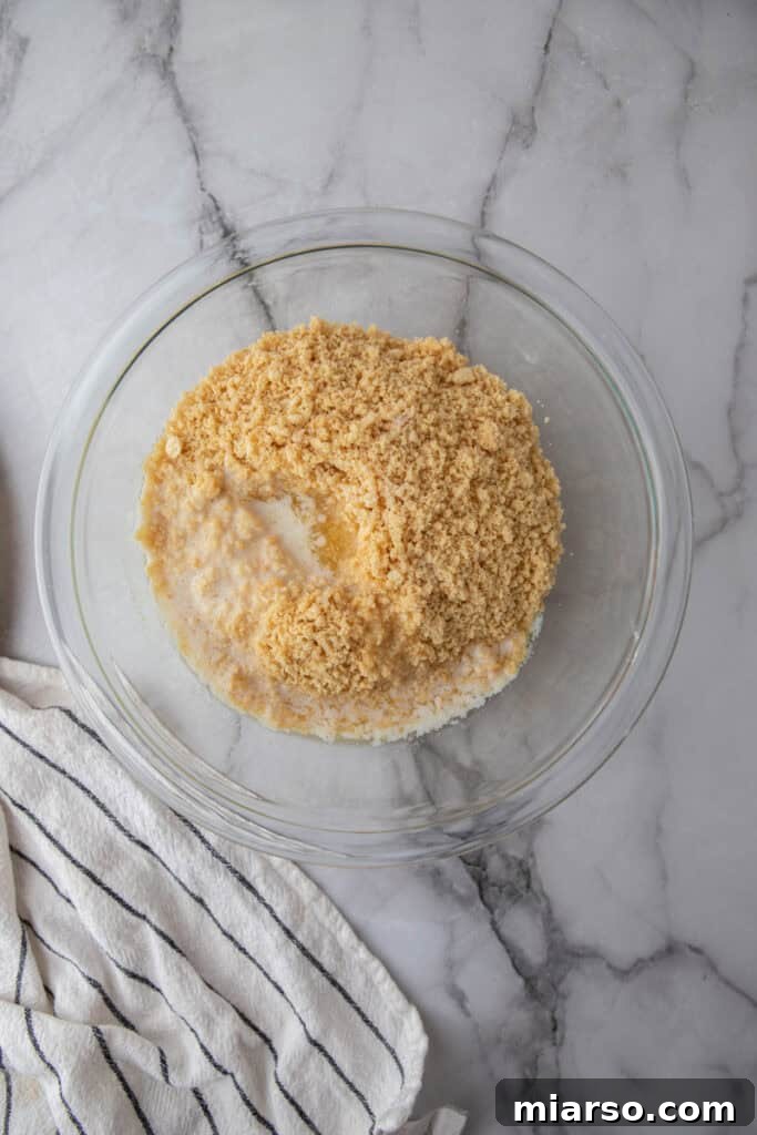 Golden Oreo Pie Crust Perfection 5 Melted butter being poured over golden Oreo crumbs in a mixing bowl.