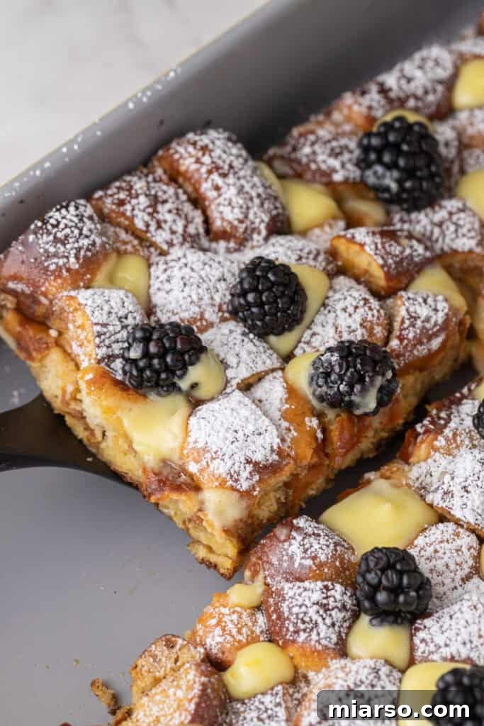A delectable slice of Pretzel French Toast Bake being carefully scooped from the baking pan, showcasing its golden-brown crust and soft, custardy interior, ready to be served.