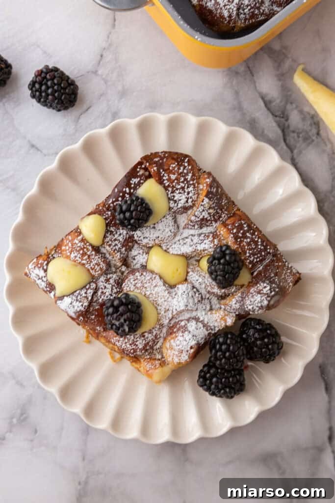 An inviting overhead shot of the golden-brown Pretzel French Toast Bake, beautifully garnished with powdered sugar and fresh berries, ready to be divided and enjoyed.