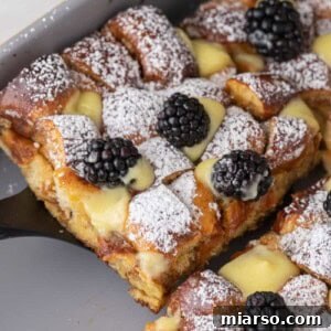 Pretzel French Toast Bake slice being scooped out of the pan, ready to be served and enjoyed.