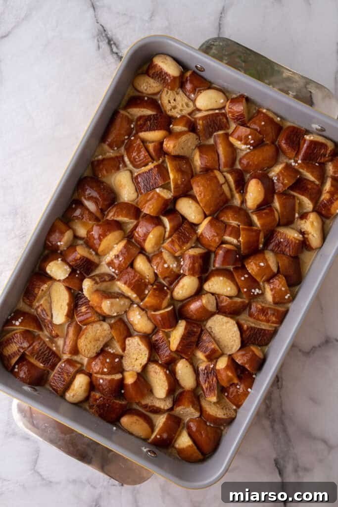 The cubed pretzel bread in the baking dish, generously covered with the creamy custard mixture, ready to be chilled.