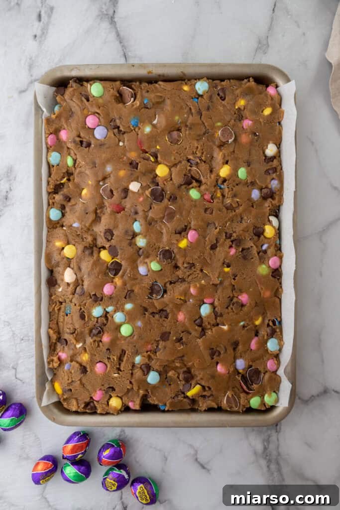 Cookie dough spread evenly in a baking pan.