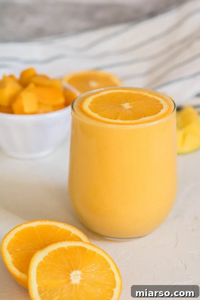 Mango orange smoothie with an orange slice on top