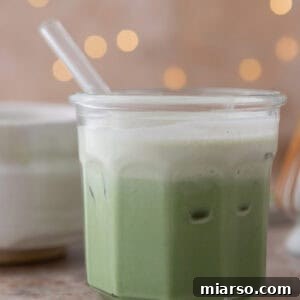 Iced salted matcha latte with a cream top and flickering lights behind it.