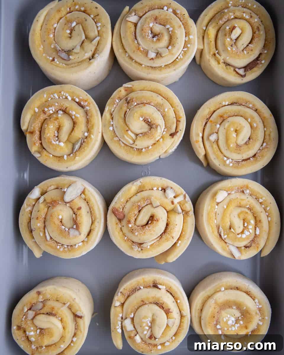 Irresistible Almond Croissant Cinnamon Rolls: Bakery-Soft and Buttery 16 Shaped almond croissant cinnamon rolls rising in baking dish