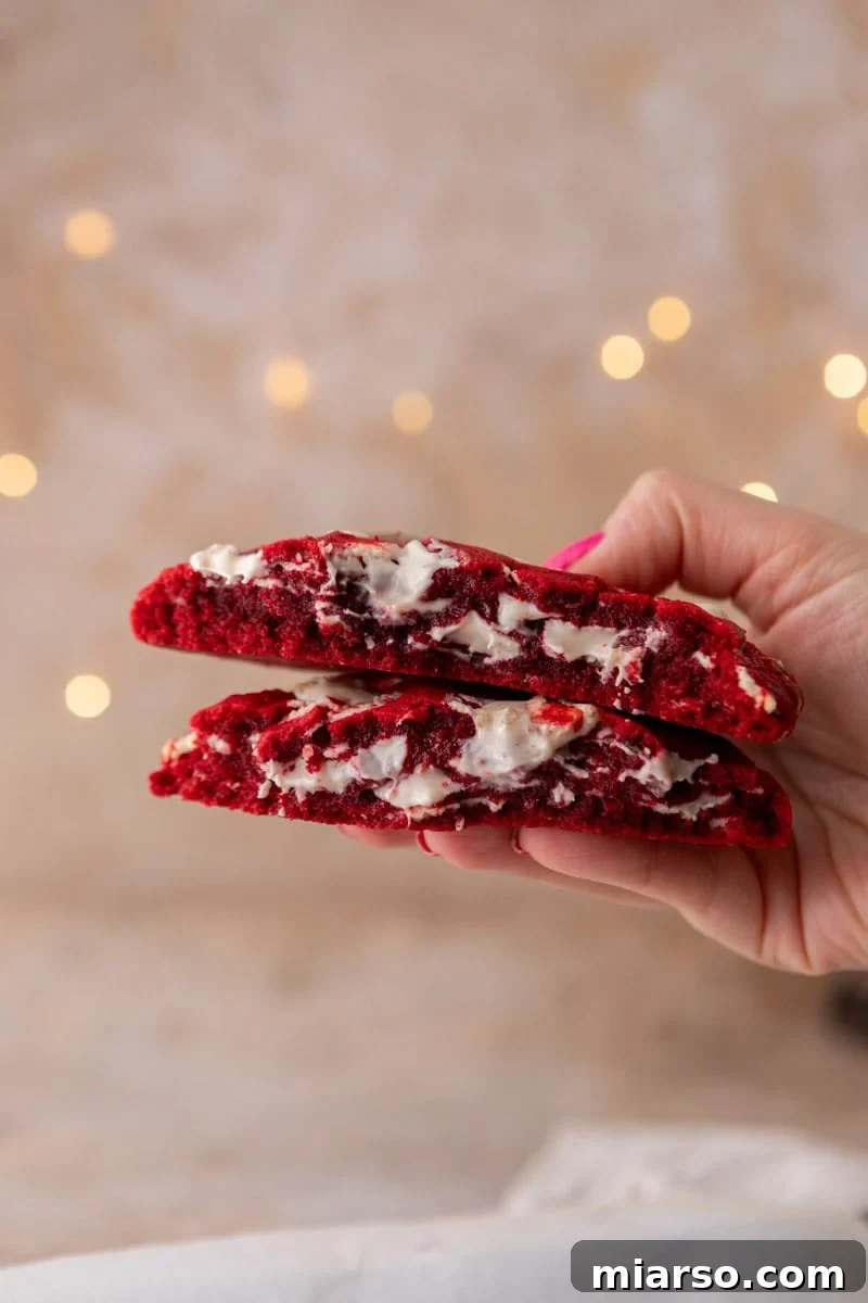 Single serve red velvet cookie broken in half showing a chewy center with white chocolate