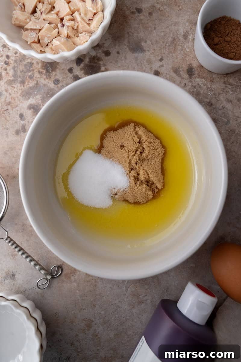 Melted butter mixed with brown sugar and white sugar in a bowl
