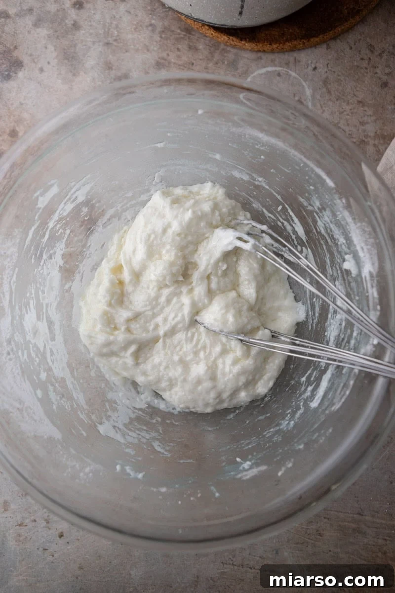 Thick, glossy tapioca dough forming in a bowl after the hot liquid mixture has been incorporated, showing its cohesive texture.