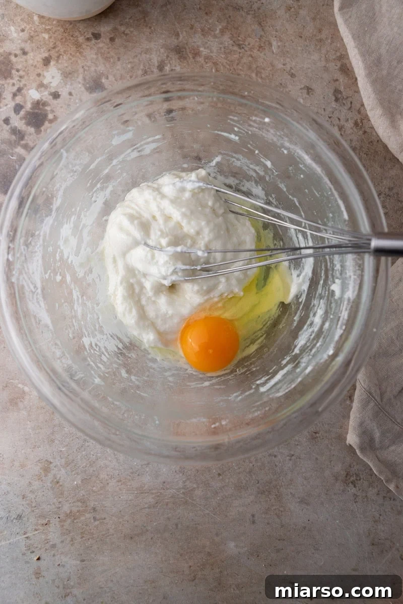 A single egg added to the warm tapioca dough, which will soon be whisked vigorously to create a smooth and elastic cheese bread batter.