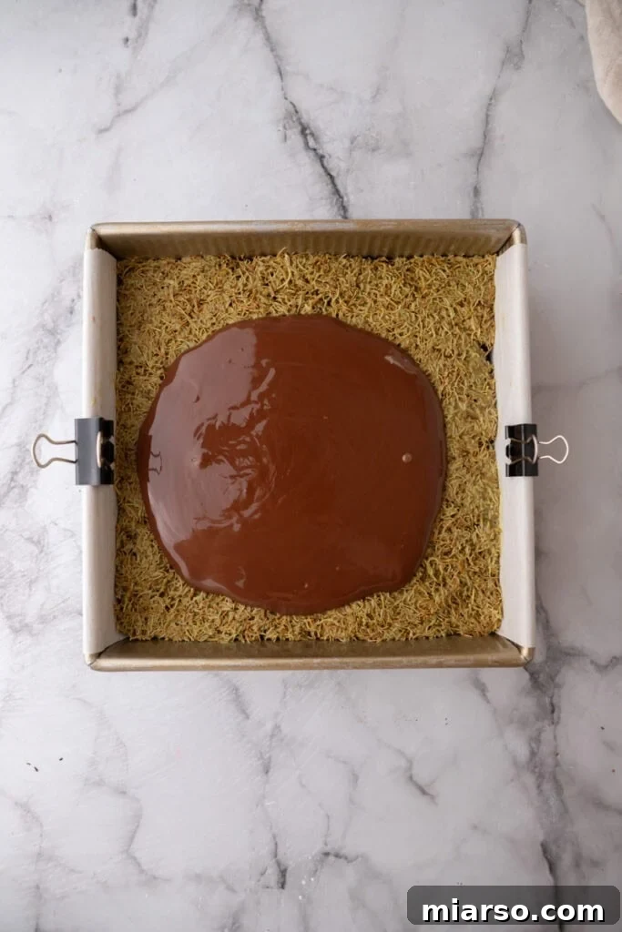 Dubai's Viral Pistachio Kunafa Brownies 19 topping going on other layers, showing chocolate topping being spread