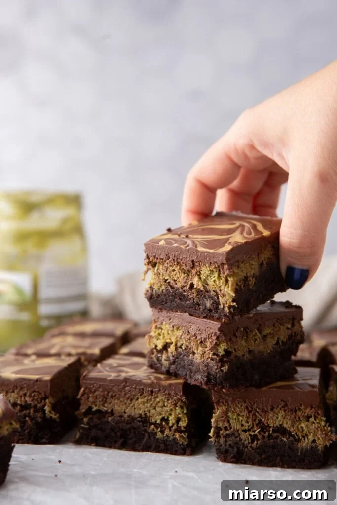Dubai's Viral Pistachio Kunafa Brownies 5 Dubai Chocolate Brownies Recipe stacked on top of each other, displaying the rich chocolate top and pistachio filling