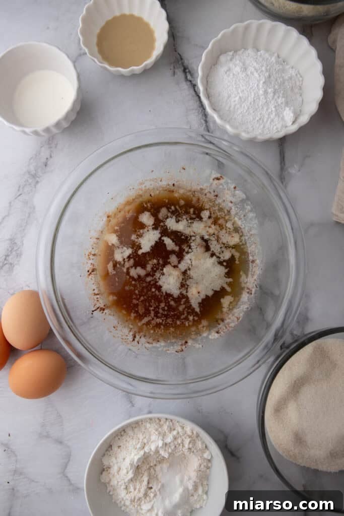 Dubai's Viral Pistachio Kunafa Brownies 7 ingredients in a bowl, showing cocoa powder being added