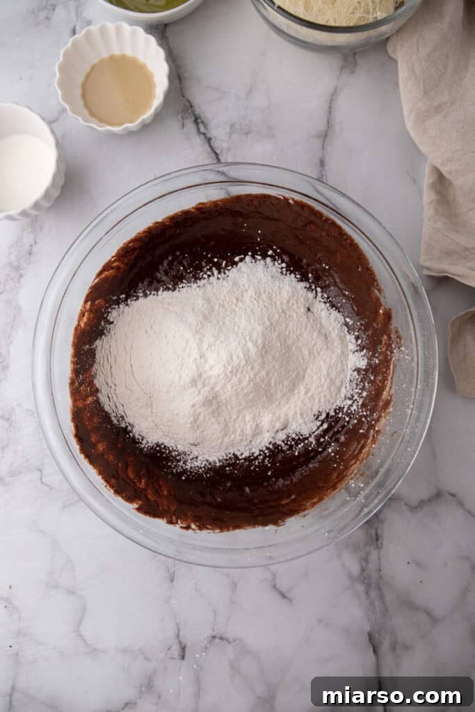 Dubai's Viral Pistachio Kunafa Brownies 10 ingredients in a bowl, showing chocolate mixture being added to egg mixture