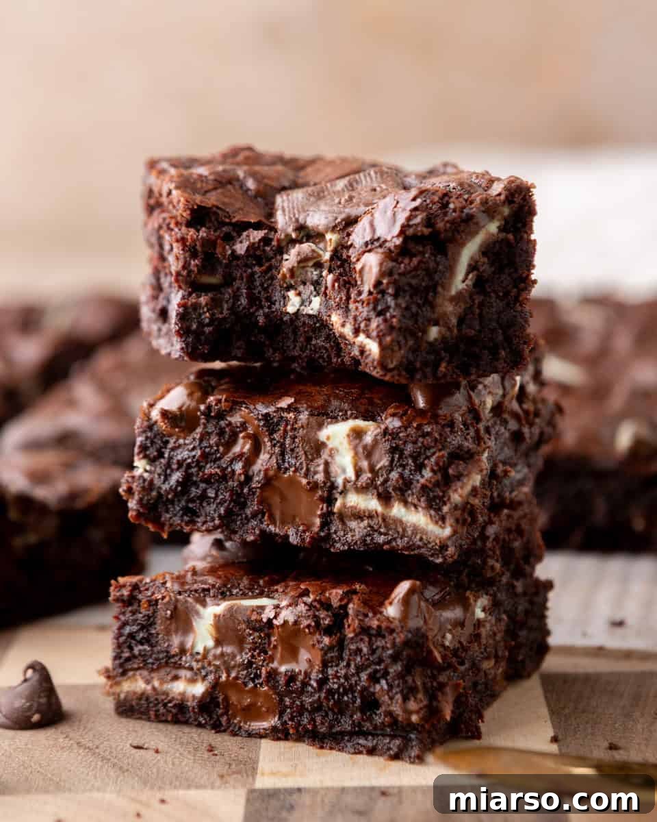 Ultra Fudgy Crinkled Andes Mint Brownies 2 Andes mint brownies stacked to show fudgy centers with melted chocolate chunks and a shiny, crackly top.