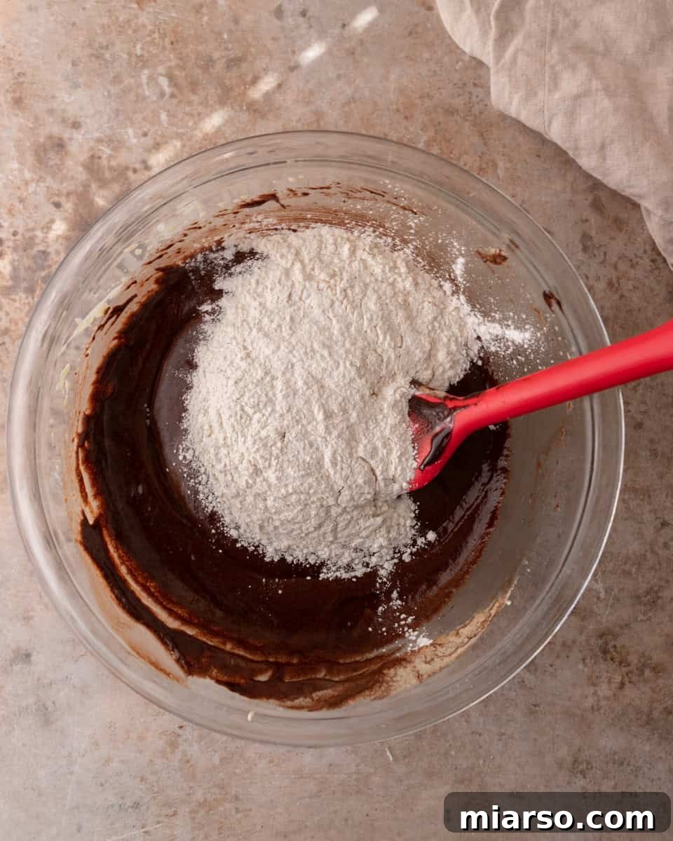 Ultra Fudgy Crinkled Andes Mint Brownies 7 Flour being added to chocolate brownie batter before the final gentle folding process.