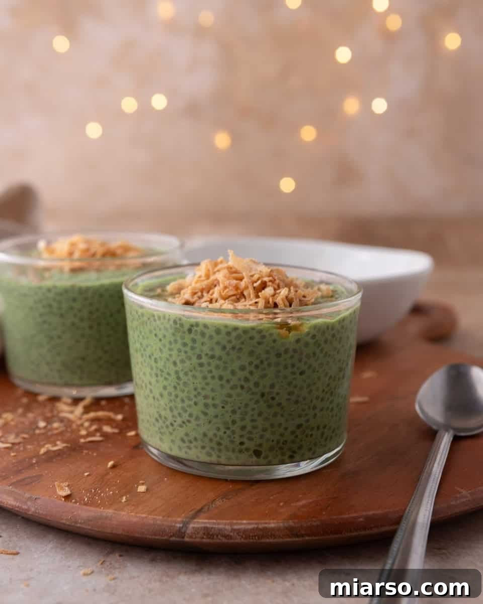 Two servings of creamy matcha chia pudding with toasted coconut topping, beautifully presented in glass jars.