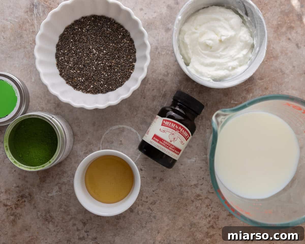 A flat lay showing all the simple ingredients required to make matcha chia pudding: chia seeds, Greek yogurt, milk, maple syrup, vanilla extract, and vibrant green matcha powder.