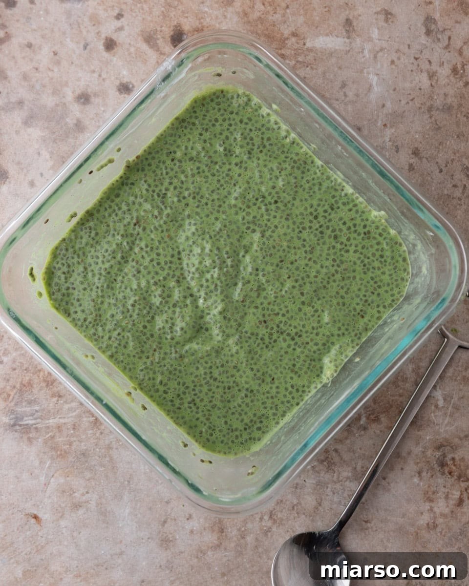 A freshly mixed bowl of vibrant green matcha chia pudding mixture, smooth and ready to be refrigerated for thickening.