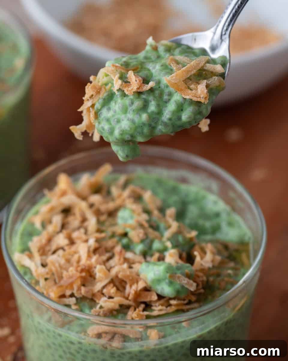 A spoon scooping a generous portion of thick, creamy matcha chia pudding, highlighting its rich texture and vibrant green color.