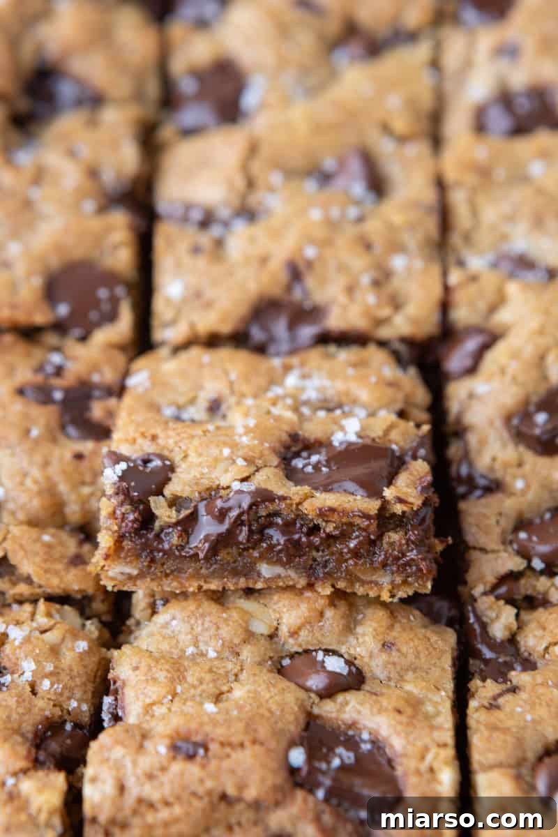 Close up of sliced chewy cookie bars with one tilted to show the gooey chocolate center and soft interior
