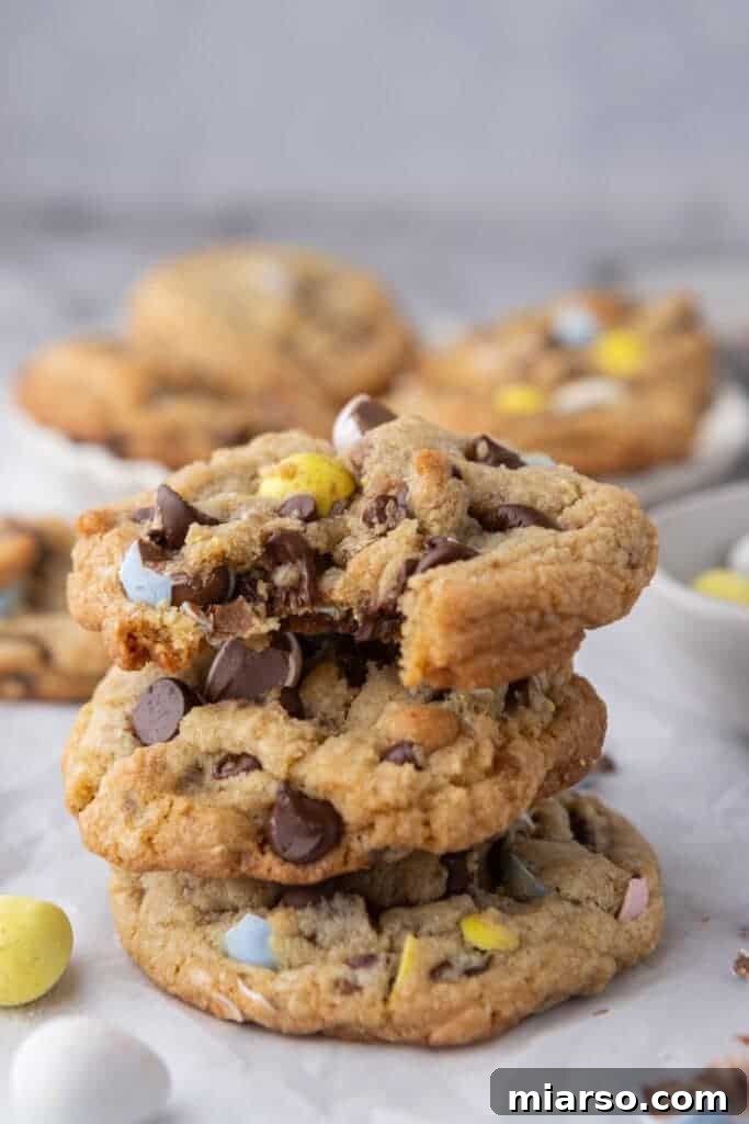 Effortless Easter Treats for Spring Gatherings 3 Stacked brown butter Cadbury mini egg cookies on parchment paper, highlighting one of the best easy Easter dessert recipes.