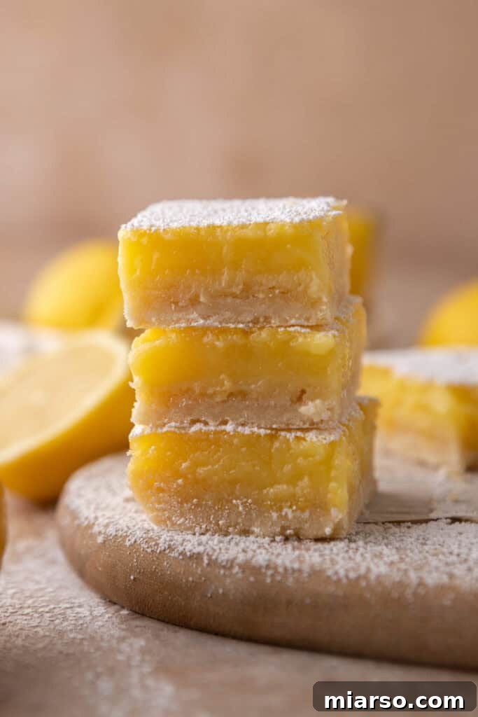 Effortless Easter Treats for Spring Gatherings 6 Classic lemon bars dusted with powdered sugar, presented on a wooden board with fresh lemons, a popular Easter dessert.