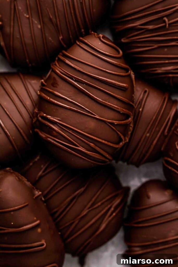Effortless Easter Treats for Spring Gatherings 7 Homemade chocolate-covered peanut butter eggs with drizzled chocolate on top, arranged on parchment paper.