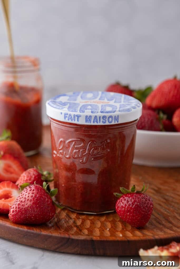 Effortless Easter Treats for Spring Gatherings 8 Homemade strawberry rhubarb jam in a Le Parfait glass jar on a wooden board surrounded by fresh strawberries.