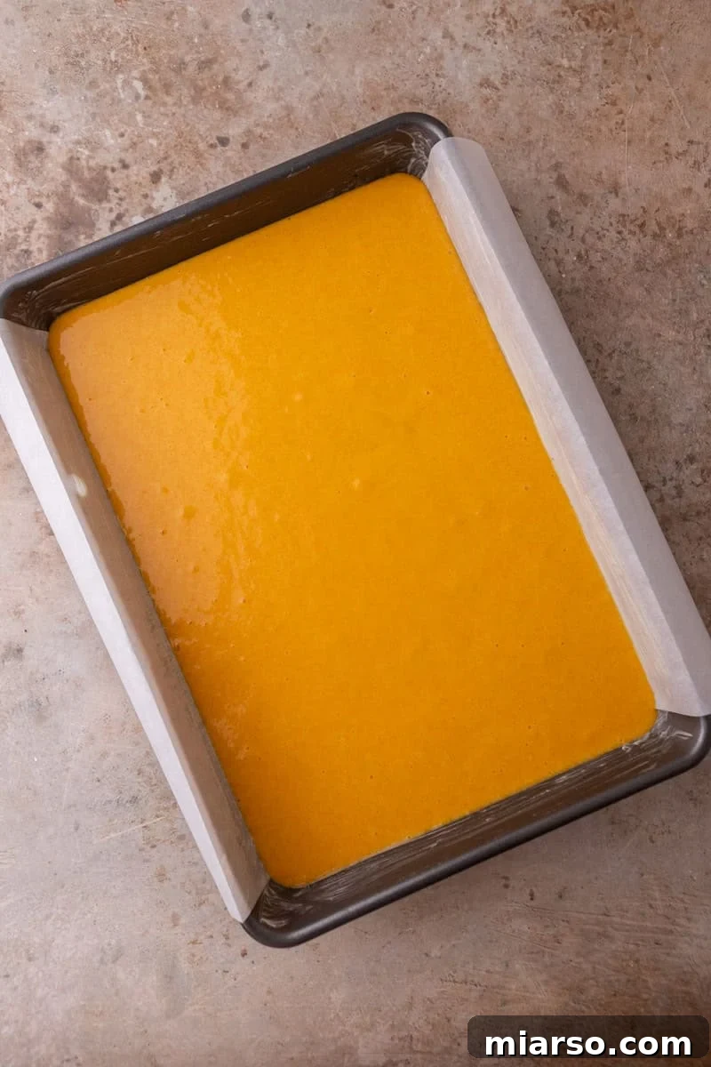 Unbaked Brazilian carrot cake batter poured into a parchment-lined 9x13 inch baking pan