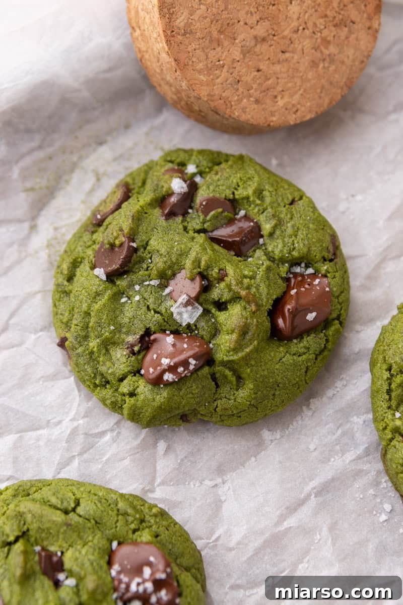Velvet Matcha Chocolate Chip Cookies 12 Close-up overhead of a baked matcha cookie topped with melted chocolate chunks and flaky sea salt