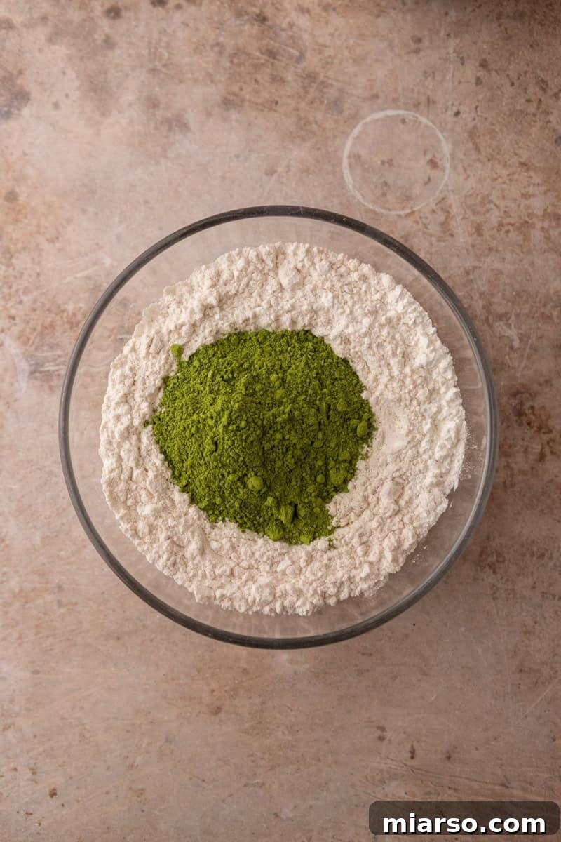 Velvet Matcha Chocolate Chip Cookies 7 Vibrant green matcha powder on top of flour in a glass bowl before whisking the dry ingredients together