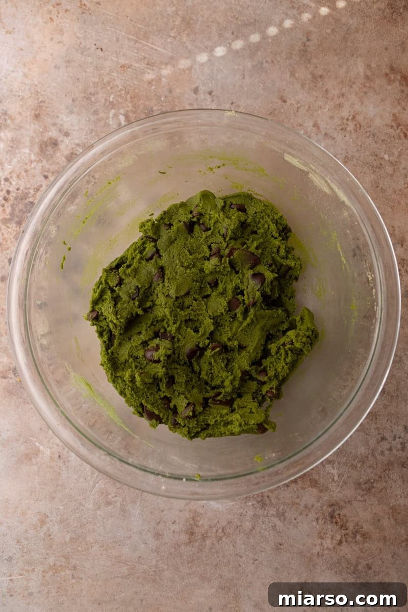 Velvet Matcha Chocolate Chip Cookies 10 Finished matcha cookie dough with chocolate chips mixed throughout in a glass bowl