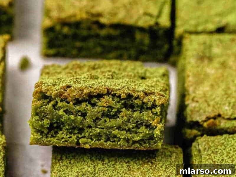 Close-up shot revealing the exquisite interior texture of vibrant green matcha brownies, highlighting their fudgy and moist consistency.