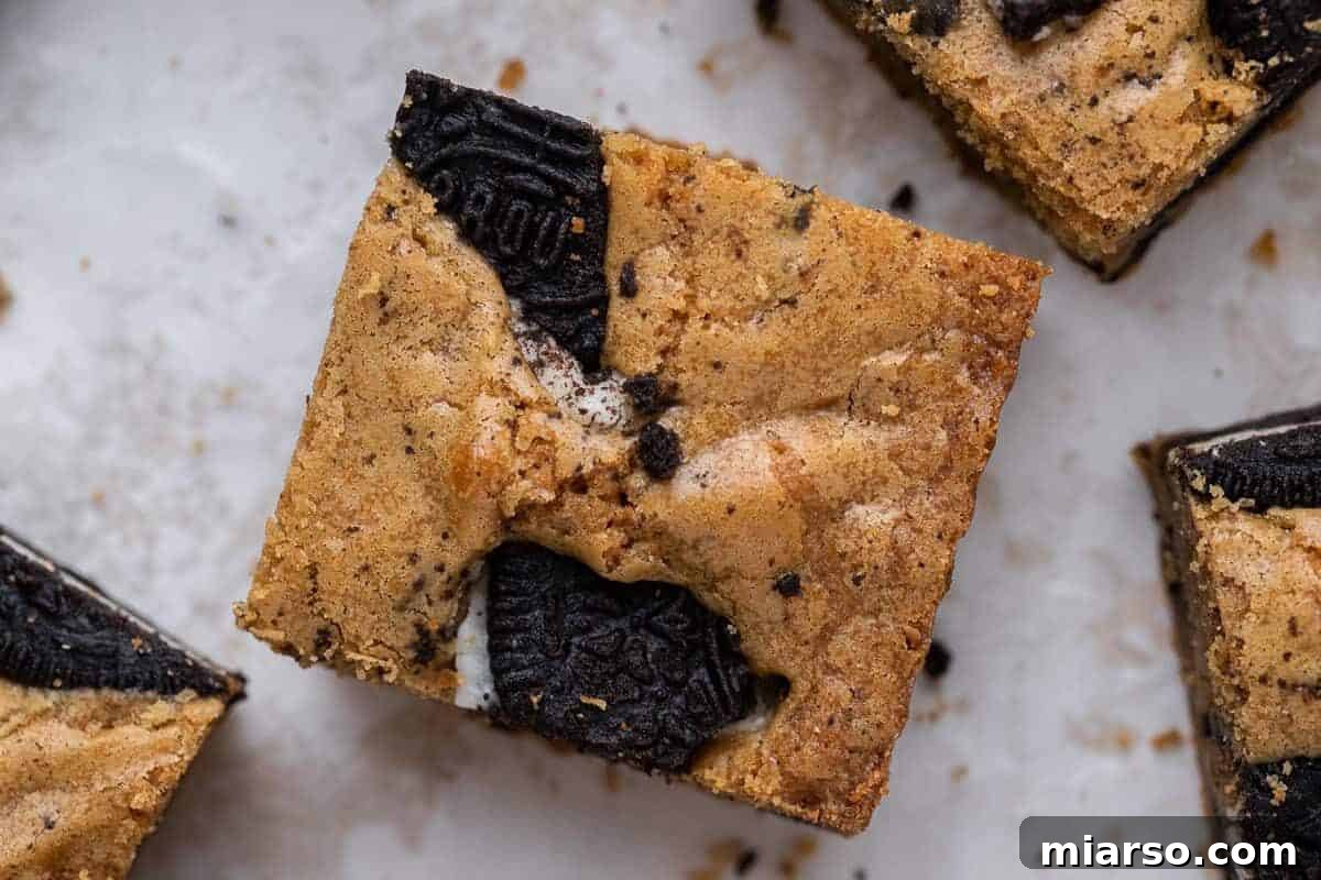 Delicious brown butter Oreo blondies, perfectly sliced into squares, revealing generous chunks of double-stuffed Oreo cookies baked throughout their chewy, golden bars.