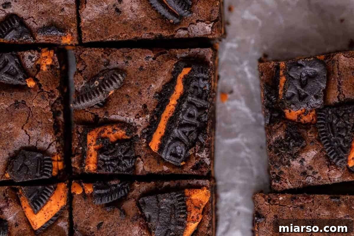 Overhead view of festive Halloween Oreo brownies, perfectly sliced into squares, featuring vibrant orange Halloween Oreo cookies playfully baked into the fudgy brownie top.