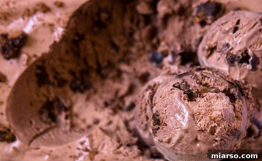 Close-up of luscious scoops of chocolate no-churn ice cream, generously mixed with delectable brownie chunks, showcasing its creamy texture and rich brownie pieces.