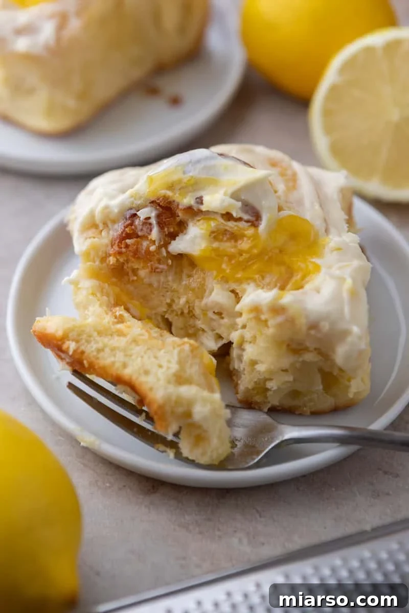 Lemon roll pulled apart on a white plate showing lemon curd pockets inside