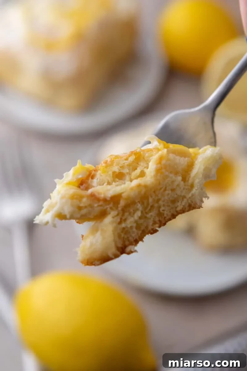 A forkful of lemon roll with lemon curd showing the soft fluffy texture inside
