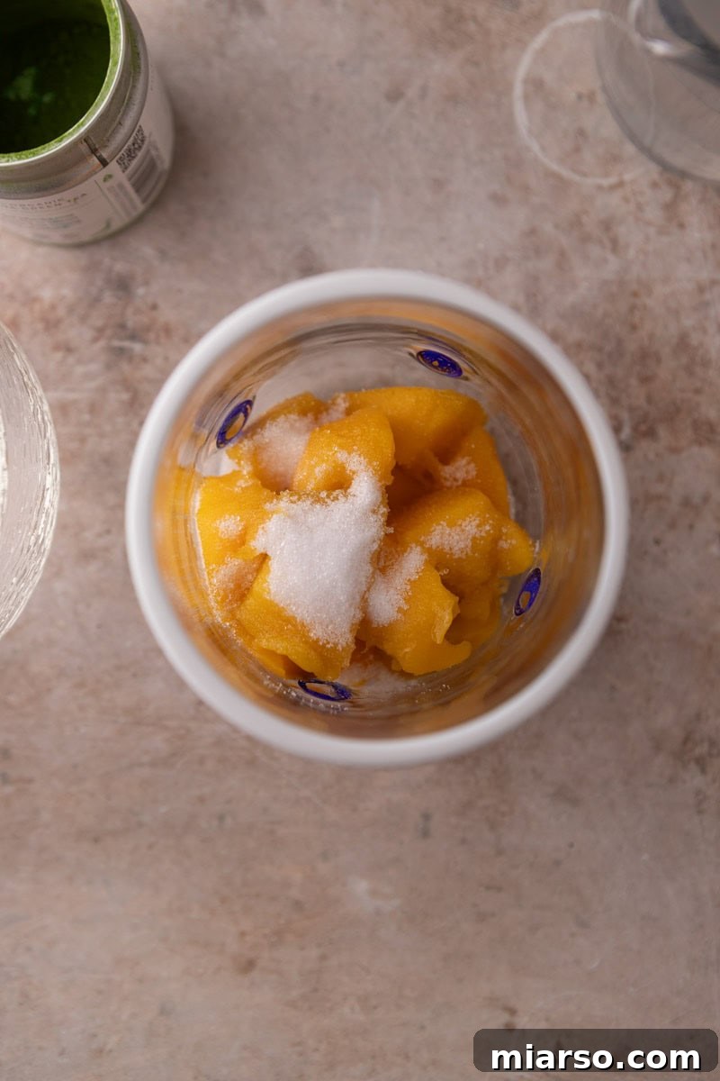 fresh mango chunks and sweetener in a wide mouth glass before blending