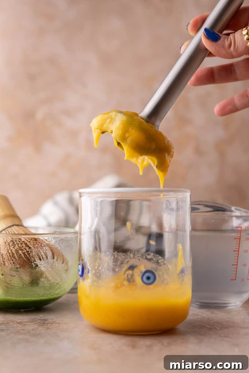 immersion blender making fresh mango puree directly in the glass