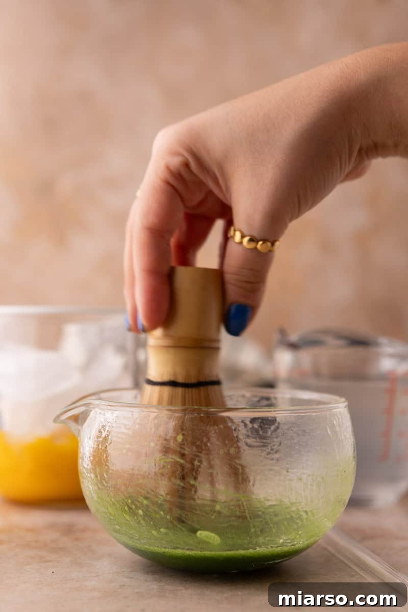 whisking matcha powder with hot water using a bamboo matcha whisk