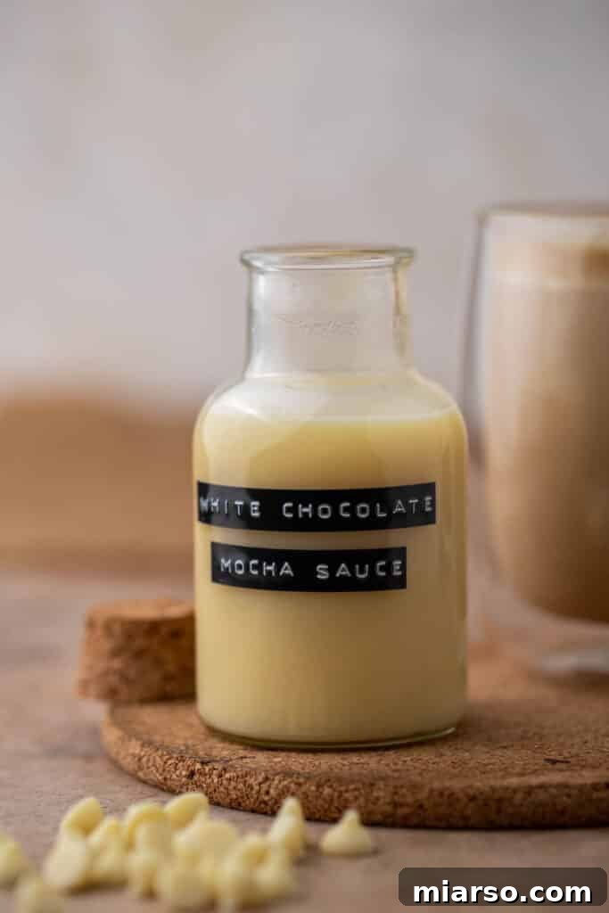 A small glass bottle filled with rich, creamy homemade white chocolate mocha sauce, ideal for decadent coffee creations.