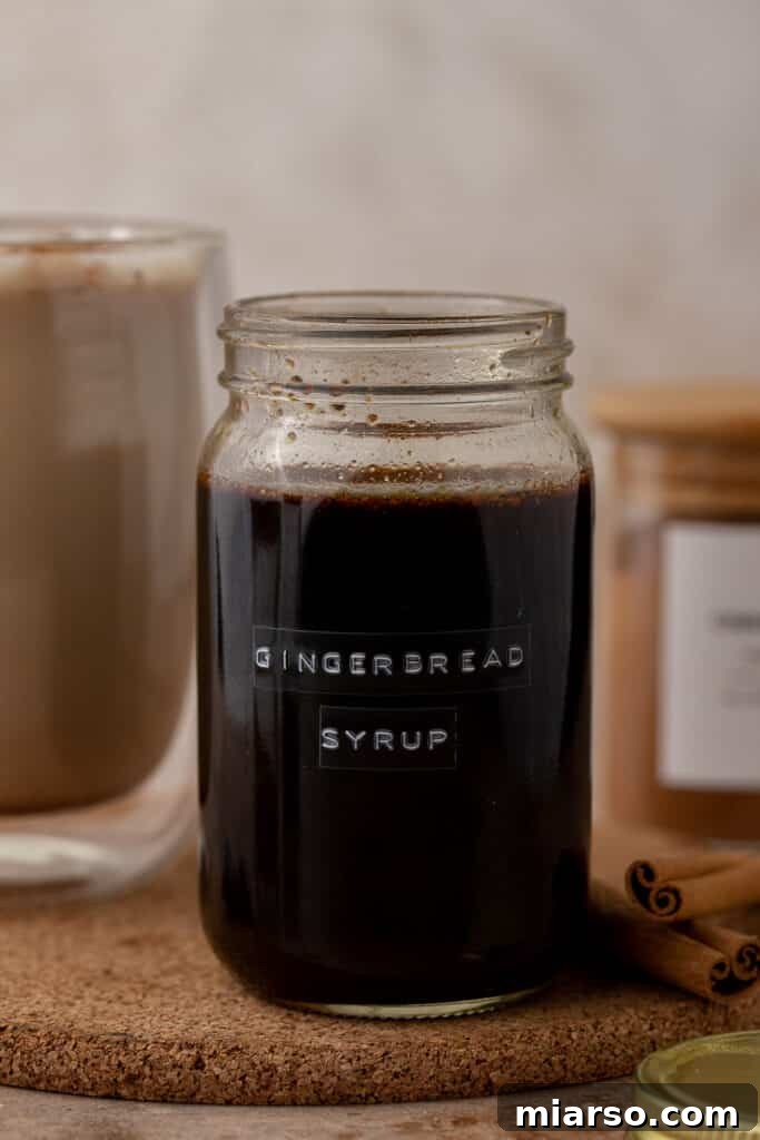 A labeled glass mason jar filled with comforting homemade gingerbread coffee syrup, ready for festive drinks.